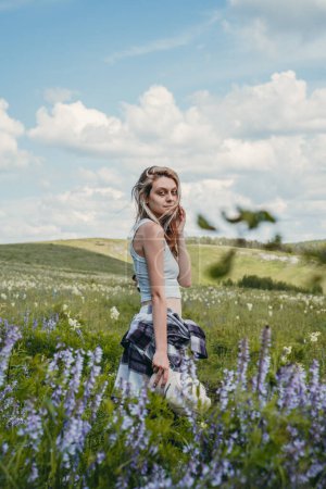 Foto de Chica atractiva en el campo con flores blancas y lila - Imagen libre de derechos