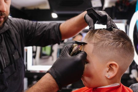 Adult male barber lining up child'sma edges in Portland, Oregon
