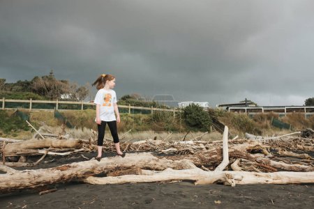 Foto de Chica de pie en madera a la deriva mirando a la playa - Imagen libre de derechos