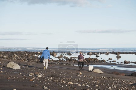 Téléchargez les photos : Père et fils marchant sur une plage rocheuse avec un chien - en image libre de droit