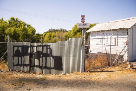 Téléchargez les photos : Graffitis illisibles et pancarte du shérif à côté d'un appât vide. - en image libre de droit