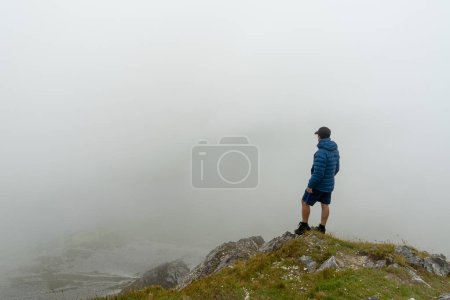 Téléchargez les photos : Homme debout au sommet de la montagne admirant le paysage avec le brouillard - en image libre de droit
