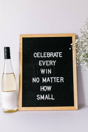 Photo for Celebration quote on letter board with baby breath and white wine - Royalty Free Image