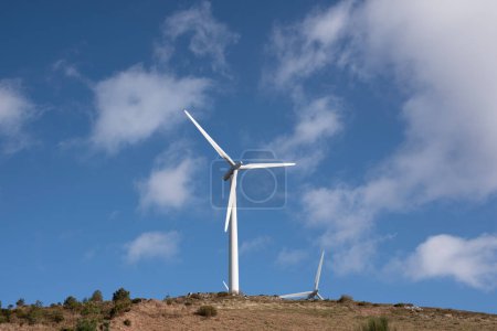 Téléchargez les photos : Éoliennes sur une montagne avec ciel bleu et nuages - en image libre de droit