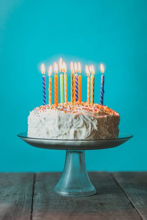 Photo for Birthday cake with white icing and candles against blue background. - Royalty Free Image