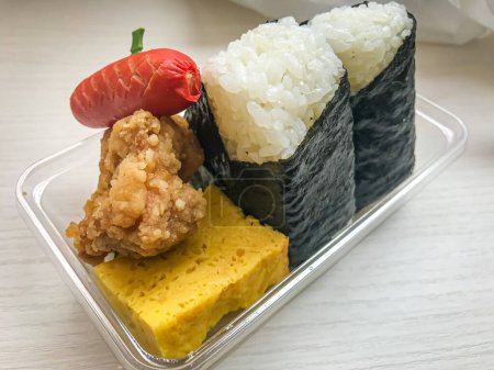 Foto de Comida rápida japonesa, dos rollos de sushi, una mini salchicha, huevo y pollo - Imagen libre de derechos