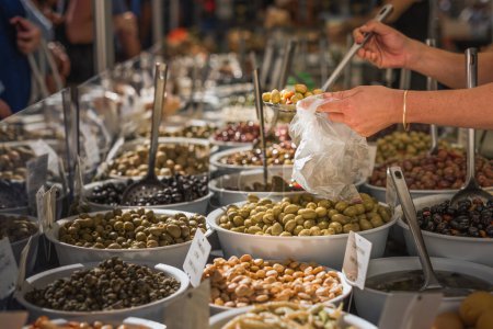 Téléchargez les photos : L'exploitant d'un étal sert des olives locales dans un étal de marché en Provence - en image libre de droit