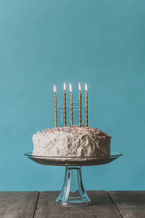 Foto de Tarta de cumpleaños con glaseado blanco y velas sobre fondo azul. - Imagen libre de derechos