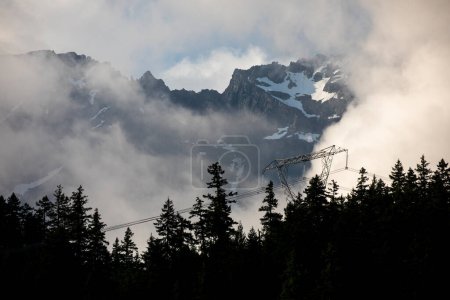 Photo for Contrast between high voltage power lines and snow covered mountain peaks behind. - Royalty Free Image