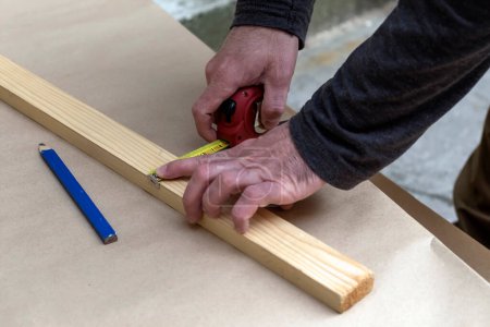 Téléchargez les photos : Charpentier mesurant un morceau de bois - en image libre de droit