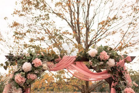 Foto de Arco de boda o cenador con flores rosadas / blancas y tela rosa - Imagen libre de derechos