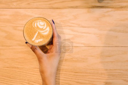 Photo for Hand holding glass of latte with rose latte art - Royalty Free Image