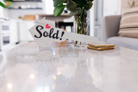 Photo for House Sold sign shaped as a key sitting on marble table - Royalty Free Image
