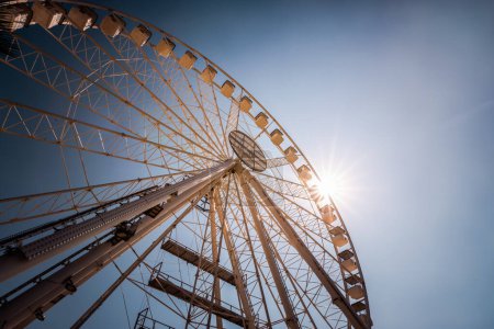 Téléchargez les photos : Plan grand angle de la grande roue ferris contre le ciel bleu avec coup de soleil - en image libre de droit