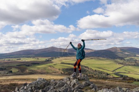 Foto de Senderista femenina de pie en la cima de la montaña sonriendo triunfalmente - Imagen libre de derechos