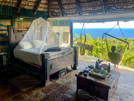 Photo for Man from behind in hammock in thatched treehouse room - Royalty Free Image
