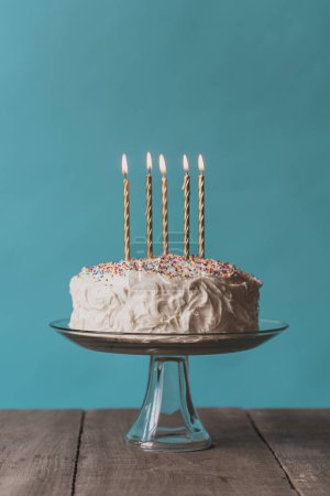 Foto de Tarta de cumpleaños con glaseado blanco y velas sobre fondo azul. - Imagen libre de derechos