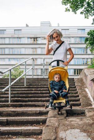 Photo for A woman rolls a stroller with a child on the ramp of the stairs - Royalty Free Image