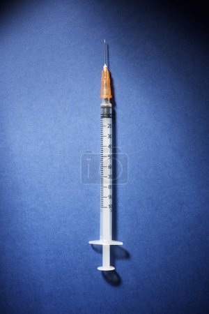 Photo for Hypodermic syringe on a blue table - Royalty Free Image