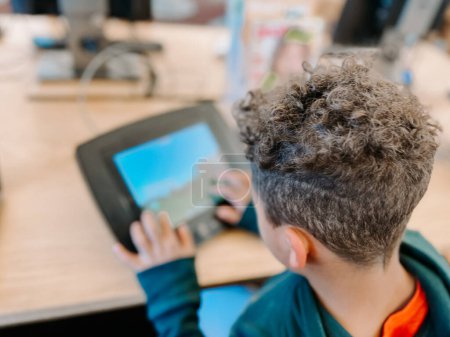 Photo for Over the shoulder view of mixed race first grader on tablet - Royalty Free Image