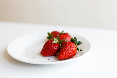 Téléchargez les photos : Fraises fraîches mûres rouges sur assiette dans la cuisine avant de faire le dessert - en image libre de droit