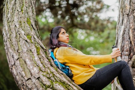 Photo for Young woman hiking and standing near a tree trunk tired - Royalty Free Image