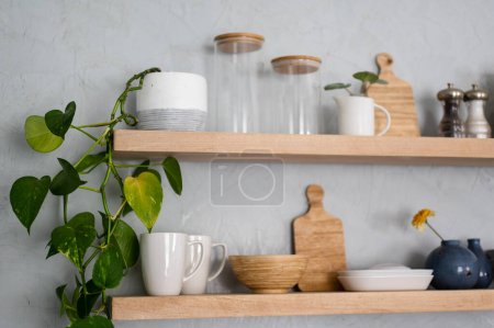 Foto de Planta en maceta y vajilla de cocina en el estante de madera moderna en la pared de yeso - Imagen libre de derechos