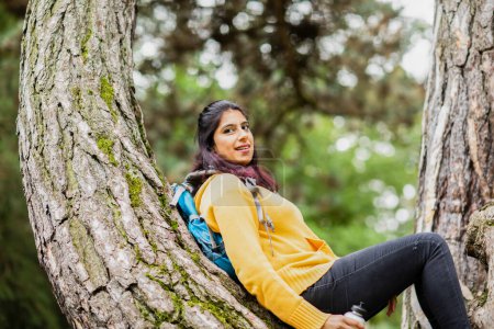 Photo for Young woman hiking and relaxing on a branch of a tree - Royalty Free Image