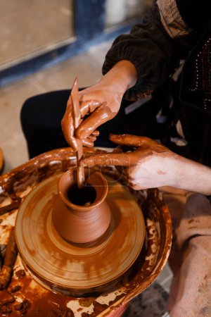 Photo for Potter with a student on the potter's wheel makes dishes from clay - Royalty Free Image