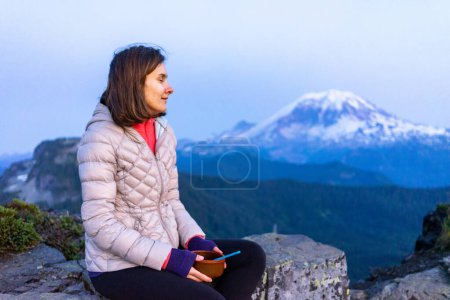 Photo for Woman hiker is eating dinner with mount Rainier in the background - Royalty Free Image