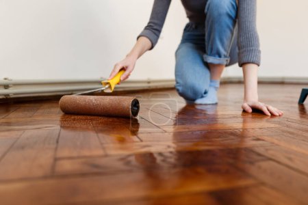 Photo for Woman in the process of varnishing the floor during the renovation - Royalty Free Image