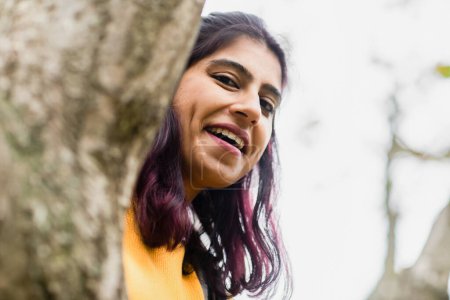 Téléchargez les photos : Jeune femme regardant derrière un arbre - en image libre de droit
