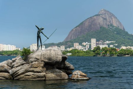 Foto de Hermosa vista a la estatua de la pesca indígena nativa con arco y flecha sobre las rocas de la laguna en Río de Janeiro, Brasil - Imagen libre de derechos
