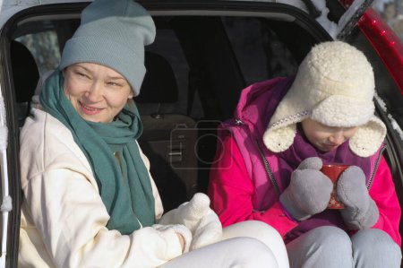 Foto de Madre e hija en un picnic sentadas en el coche - Imagen libre de derechos