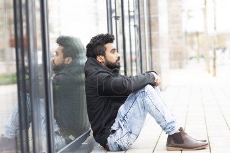 Téléchargez les photos : Jeune homme assis dehors sur le fond - en image libre de droit