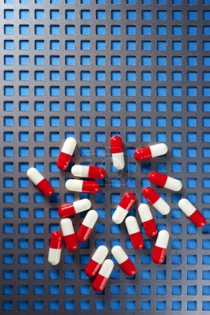Photo for Red and white pills on a metal grid. - Royalty Free Image