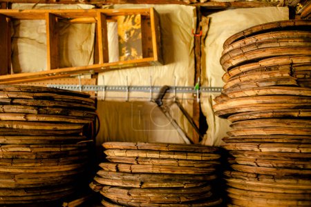 Photo for Stacks of wood bourbon barrel lids lean on  wall lined with tools - Royalty Free Image