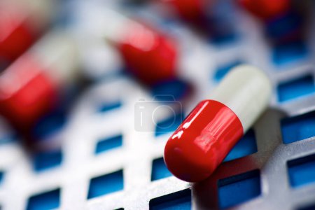 Téléchargez les photos : Pilules rouges et blanches sur une grille métallique. - en image libre de droit