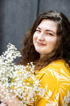 Photo for A girl in a yellow T-shirt with a bouquet of small white flowers - Royalty Free Image