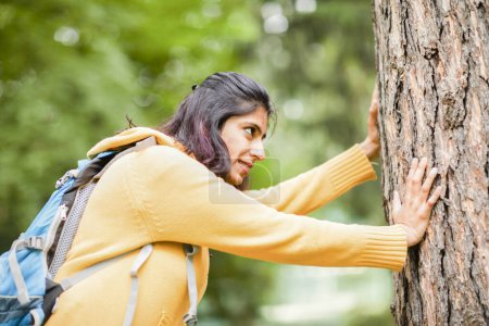 Téléchargez les photos : Jeune femme poussant un arbre avec force - en image libre de droit