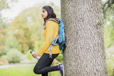 Téléchargez les photos : Jeune femme randonnée et détente sur un arbre - en image libre de droit