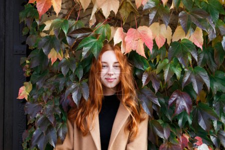 Téléchargez les photos : Jeune femme aux cheveux roux élégant sur le fond de feuilles vertes - en image libre de droit