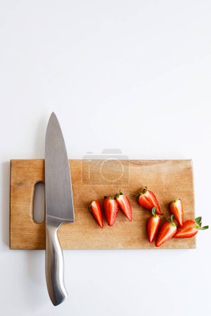 Téléchargez les photos : Couteau aux fraises repose sur une planche à découper en bois dans la cuisine - en image libre de droit