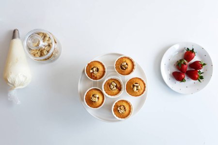 Téléchargez les photos : Fraises, muffins et crème au milieu de la cuisine, pendant la cuisson - en image libre de droit