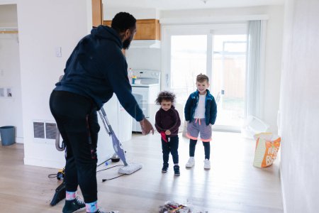 Téléchargez les photos : Papa montrant et enseignant aux enfants comment nettoyer et balayer - en image libre de droit