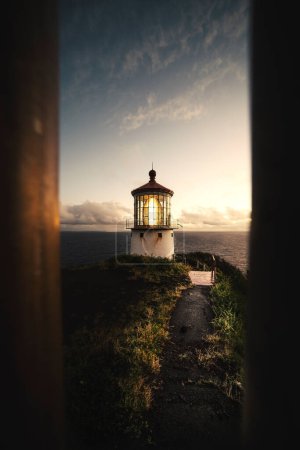 Téléchargez les photos : Lever de soleil regardant à travers une clôture à un phare à Hawaï - en image libre de droit