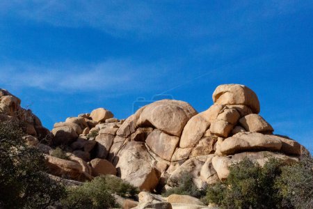 Rounded boulders stack under blue sky in Joshua Tree