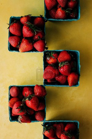 Fresh strawberries in boxes on yellow background 