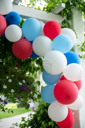 Decoración de globos rojos, blancos y azules en el arco del jardín de cerca