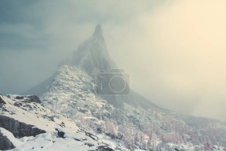The jagged spire of Prusik Peak peeks through the clouds in the